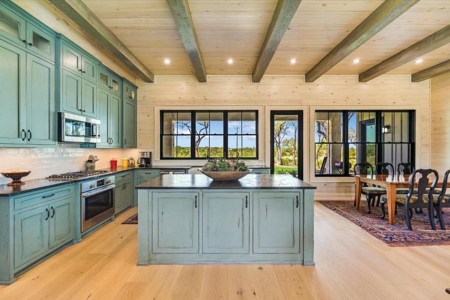 Kitchen with wood walls, green cabinetry, a center island, recessed lighting, and light wood-style floors