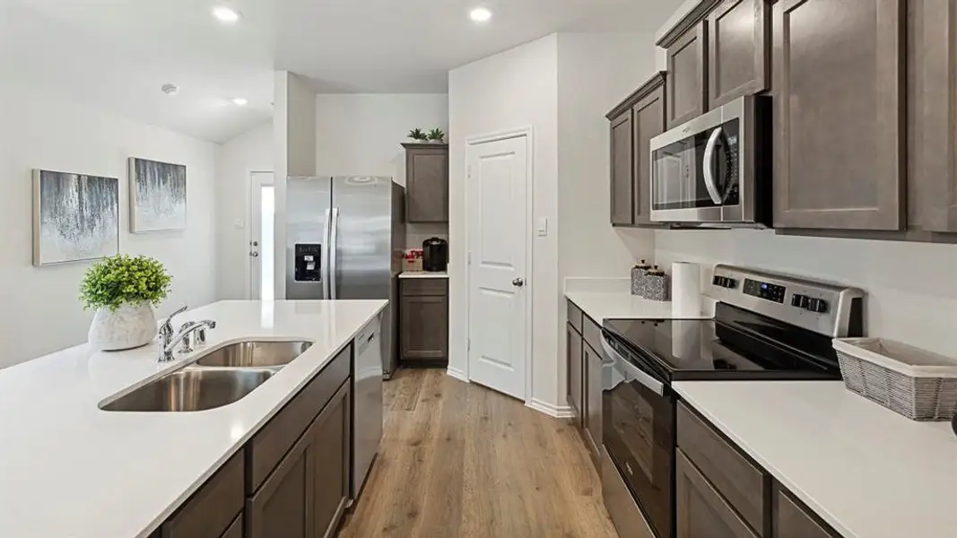Kitchen with stainless steel appliances, light wood-type flooring, dark wood finish cabinets, vaulted ceiling, and recessed lighting Kitchen with stainless steel appliances, light wood-type flooring, dark wood finish cabinets, vaulted ceiling, and recessed lighting