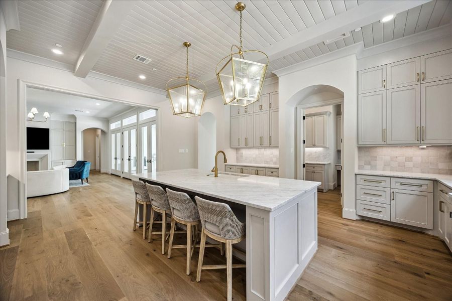 Incredible chef’s kitchen opens to the living area featuring a large island with breakfast bar seating, honed marble slab countertops, gorgeous tile backsplash and lantern pendant lighting. Custom built cabinetry, under-cabinet lighting and soft-close drawers and doors are complemented by high-end Thermador stainless appliances and a Blanco undermount sink.