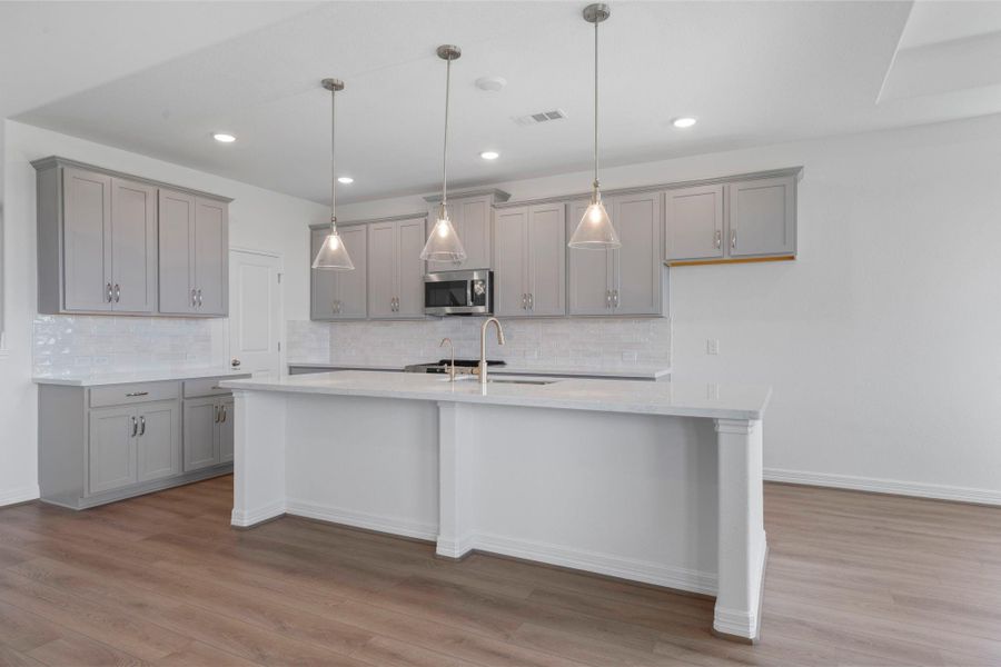 This light and bright kitchen features a large quartz island, white cabinets, a large sink overlooking your family room, recessed lighting, and beautiful backsplash. This light and bright kitchen features a large quartz island, white cabinets, a large sink overlooking your family room, recessed lighting, and beautiful backsplash.