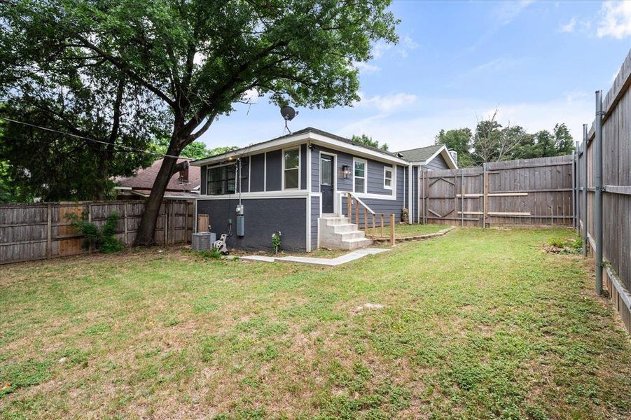 Back of property with a fenced backyard, brick siding, and entry steps Back of property with a fenced backyard, brick siding, and entry steps
