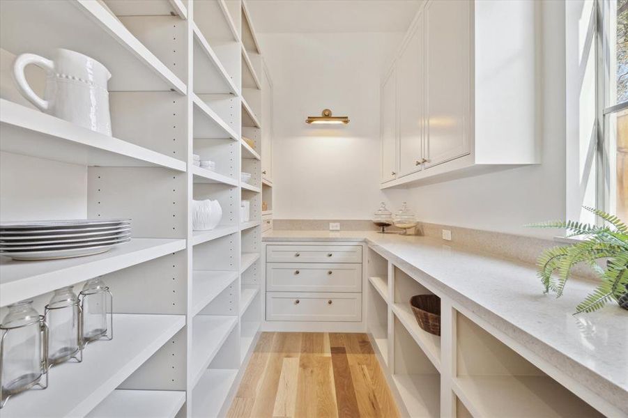 The chef pantry with a window for natural light, tons of cabinetry, prep area and art light.