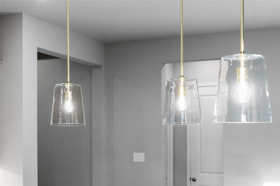 Three exquisite pendant lights elegantly hang above the kitchen island, providing focused task lighting and a touch of refined style.