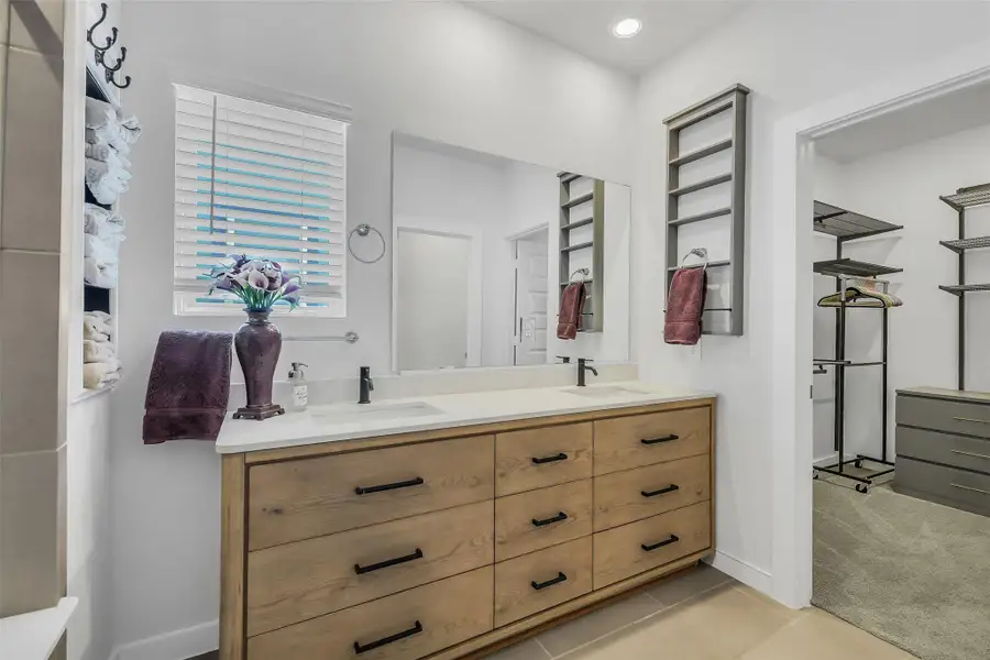 Elegant primary bathroom with dual vanities, generous counter space, modern cabinetry, and designer lighting.