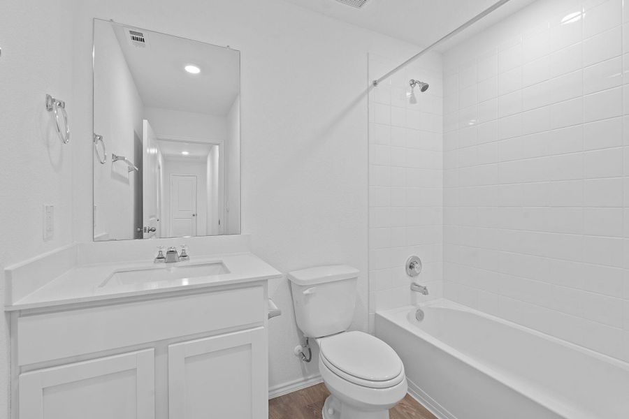 Bathroom with tub / shower combination, vanity, and dark wood finished floors