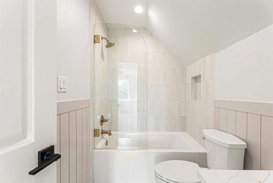 Bathroom with bathing tub / shower combination, a wainscoted wall, vaulted ceiling, and vanity