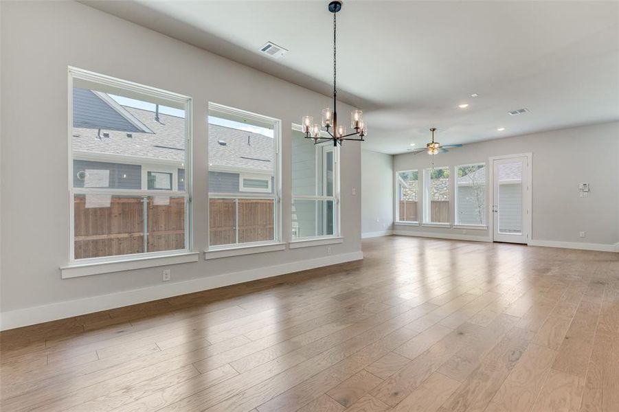 Unfurnished living room with ceiling fan with notable chandelier and light hardwood / wood-style flooring