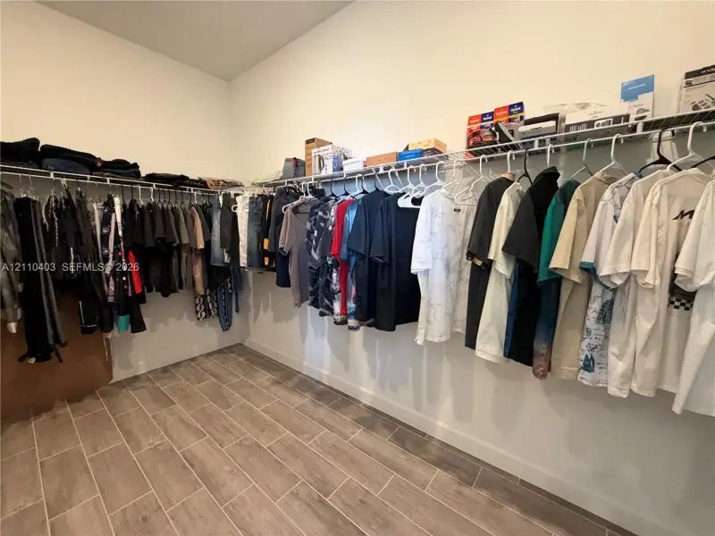 Walk-in storage space featuring wood-finish tile flooring and tiered wire shelving