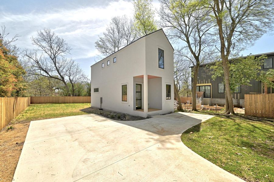 Frontr view of house featuring stucco siding, a patio, a lawn, and fence