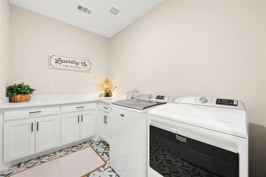 Laundry room with cabinets, washing machine and dryer, and light tile floors