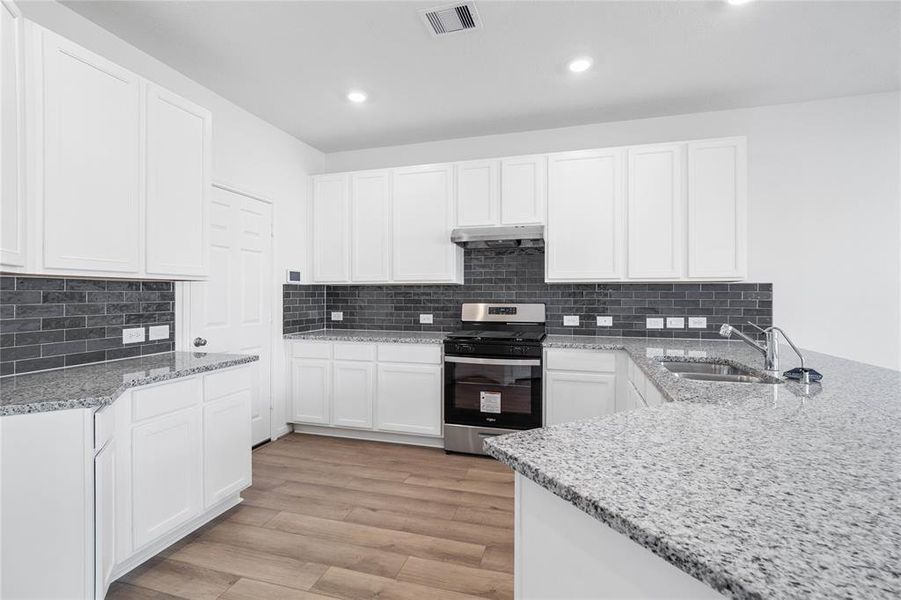 This spacious kitchen features high ceilings, stained wood cabinets, granite countertops, SS appliances, modern tile backsplash, recessed lighting, space for a breakfast bar, and a pantry all overlooking your huge family room.