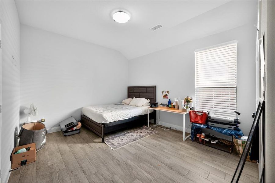 Bedroom featuring light wood-style flooring and lofted ceiling