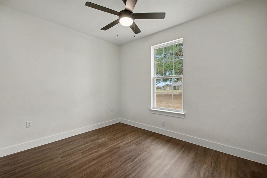 Empty room with dark wood finished floors and a ceiling fan
