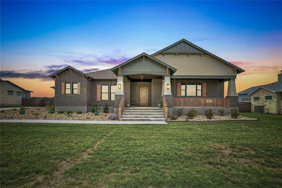 Craftsman-style house featuring a porch, a yard, and brick siding