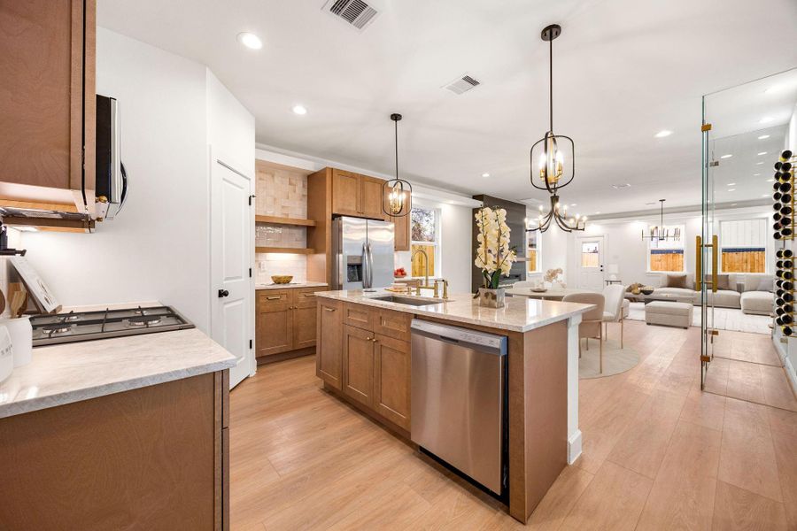 A beautifully designed kitchen showcases warm wood cabinetry, sleek countertops, and modern pendant lighting, all thoughtfully arranged around a generous island that anchors the space.