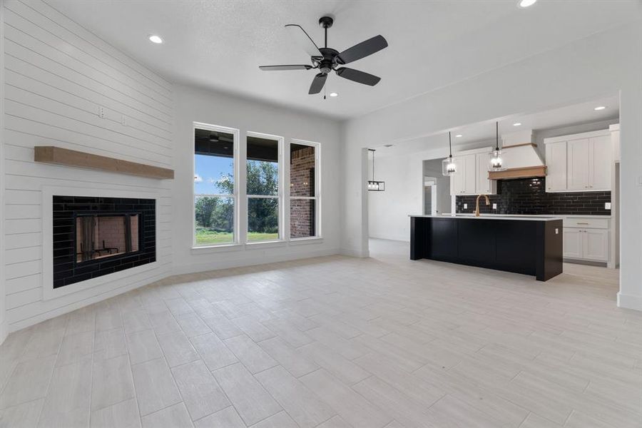 Unfurnished living room with ceiling fan, recessed lighting, a large fireplace, and light wood-style floors