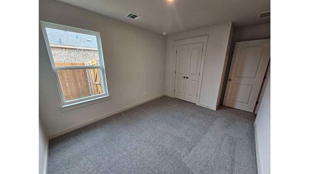 Room with light gray carpeting, a single-pane window, and white trim