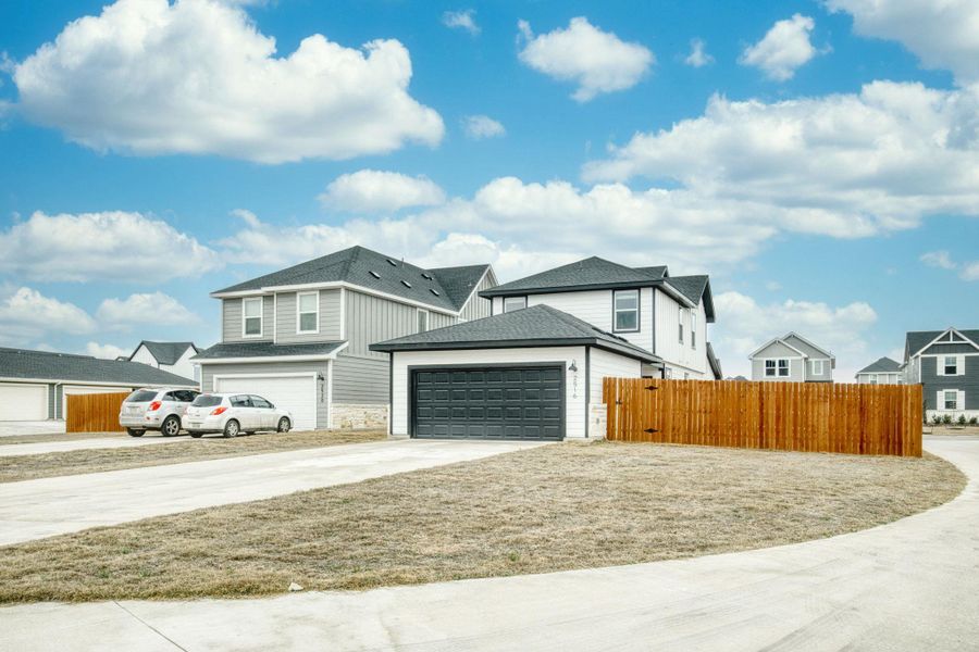 View of front of house featuring a garage, fence, concrete driveway, and roof with shingles