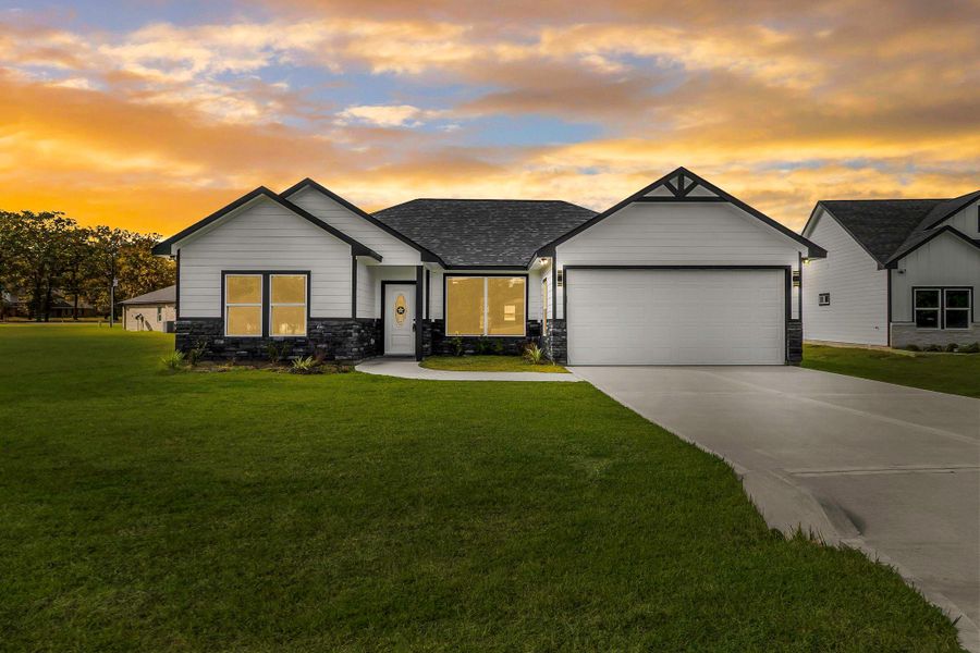 This charming single-story home features a modern design with a white and black exterior, complemented by a well-maintained lawn. It includes a spacious driveway leading to a two-car garage. The setting sun creates a warm, inviting atmosphere.