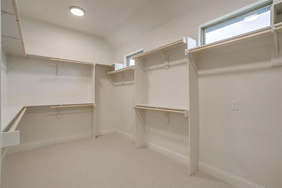 Spacious closet with vaulted ceiling and light colored carpet