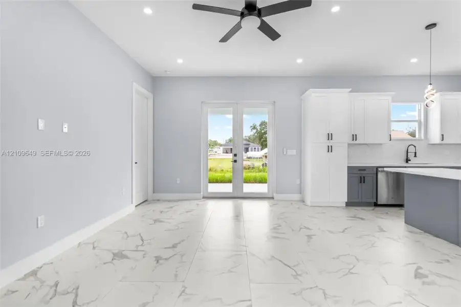Large-format tile flooring, dual-tone cabinetry, stainless steel appliances, matte black hardware, and double glass-paneled exterior doors