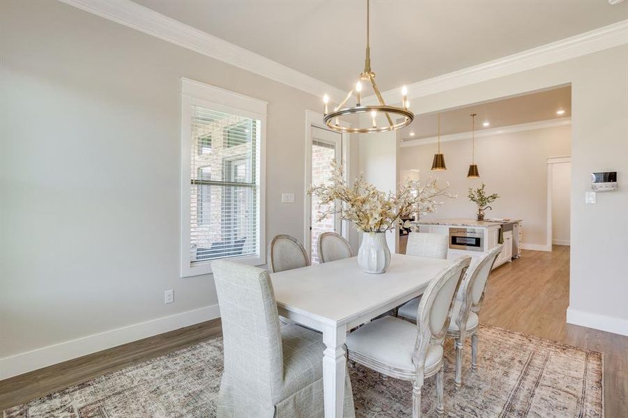 Dining area featuring a modern chandelier, crown molding, and wood-finish flooring