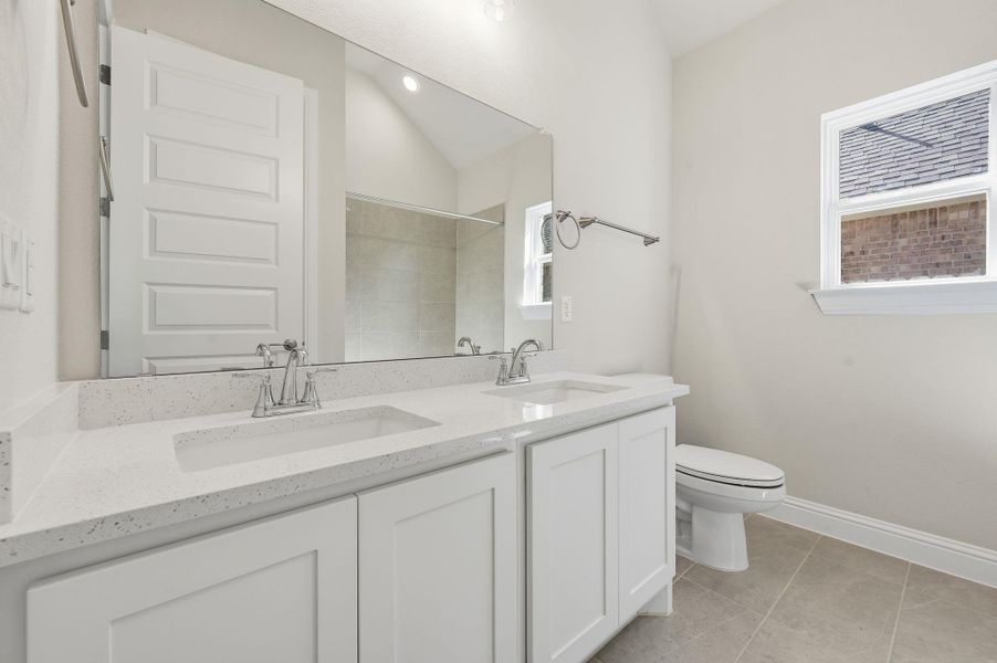 Bathroom featuring double vanity, light tile patterned floors, and a shower Bathroom featuring double vanity, light tile patterned floors, and a shower