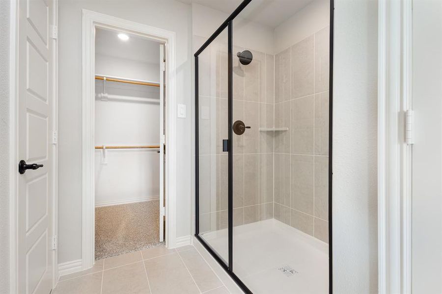 Bathroom featuring a stall shower, a spacious closet, and tile patterned flooring