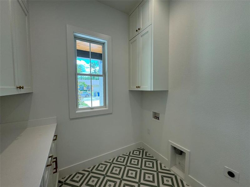 Clothes washing area featuring light tile patterned flooring, electric dryer hookup, cabinets, and hookup for a washing machine