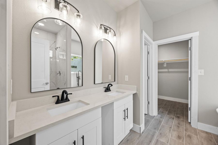 Full bath featuring a sink, a spacious closet, double vanity, and a stall shower Full bath featuring a sink, a spacious closet, double vanity, and a stall shower