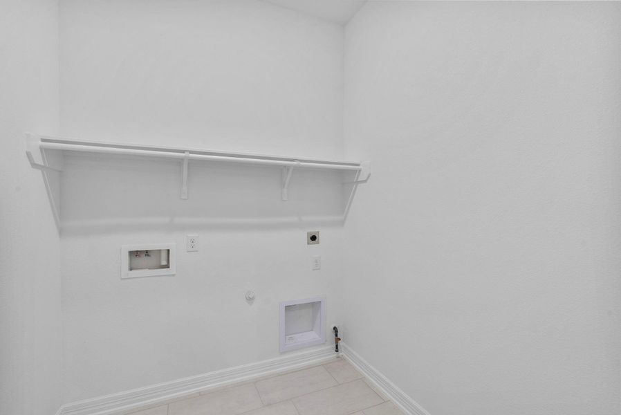 Functional utility room with custom shelving and convenient laundry hookups.