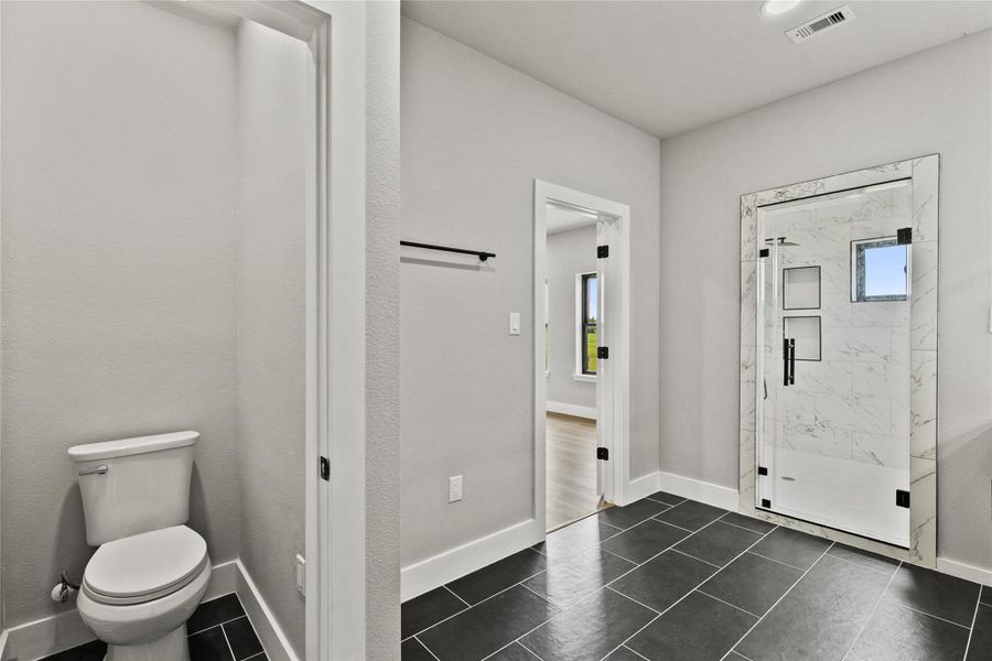 Spa-inspired primary bath featuring a fully tiled wet room with a freestanding soaking tub, dual shower heads, double vanities, illuminated mirror, and a private water closet. Thoughtfully designed with both style and functionality in mind.