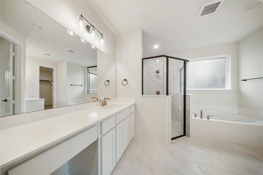 Bathroom featuring a bath, a marble finish shower, a spacious closet, vanity, and light marble finish flooring