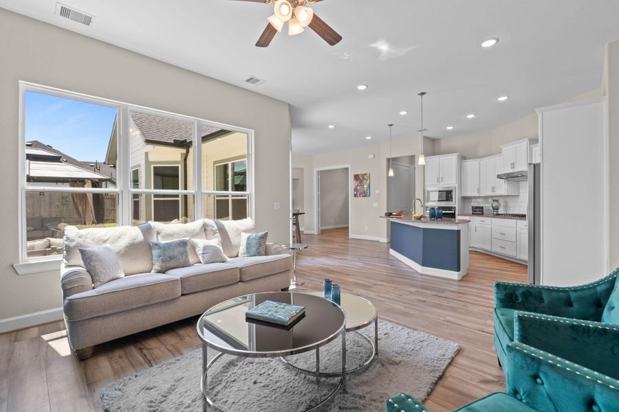 The Portico living room is filled with abundant natural light from expansive windows, creating a bright and welcoming space perfect for everyday living and entertaining. Image depicts home as-is.