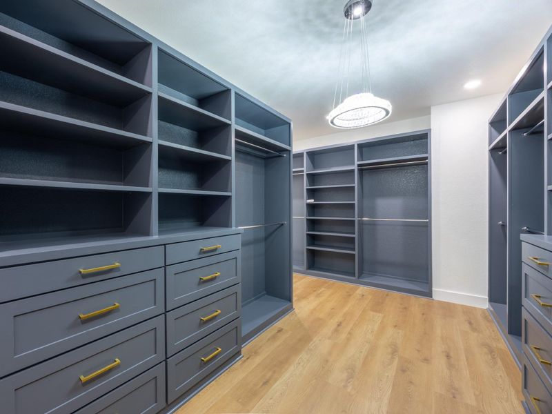 This custom walk-in closet offers the ultimate in organization and style, featuring double-sided built-ins, open shelving, and deep drawer storage for a clutter-free lifestyle. This custom walk-in closet offers the ultimate in organization and style, featuring double-sided built-ins, open shelving, and deep drawer storage for a clutter-free lifestyle.