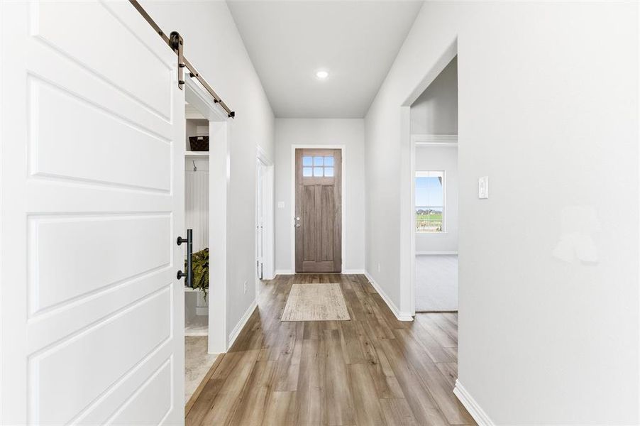 Entryway featuring a barn door, light wood finished floors, and recessed lighting