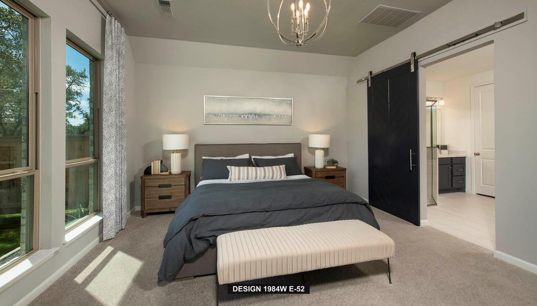Carpeted bedroom with a barn door, ensuite bathroom, and a chandelier