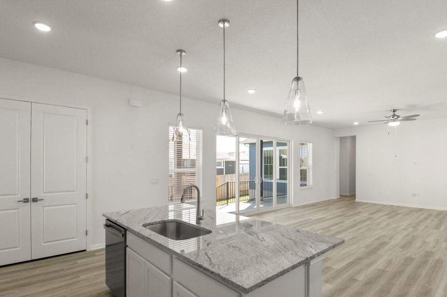 Kitchen with recessed lighting, light wood finished floors, white cabinetry, light stone counters, and pendant lighting