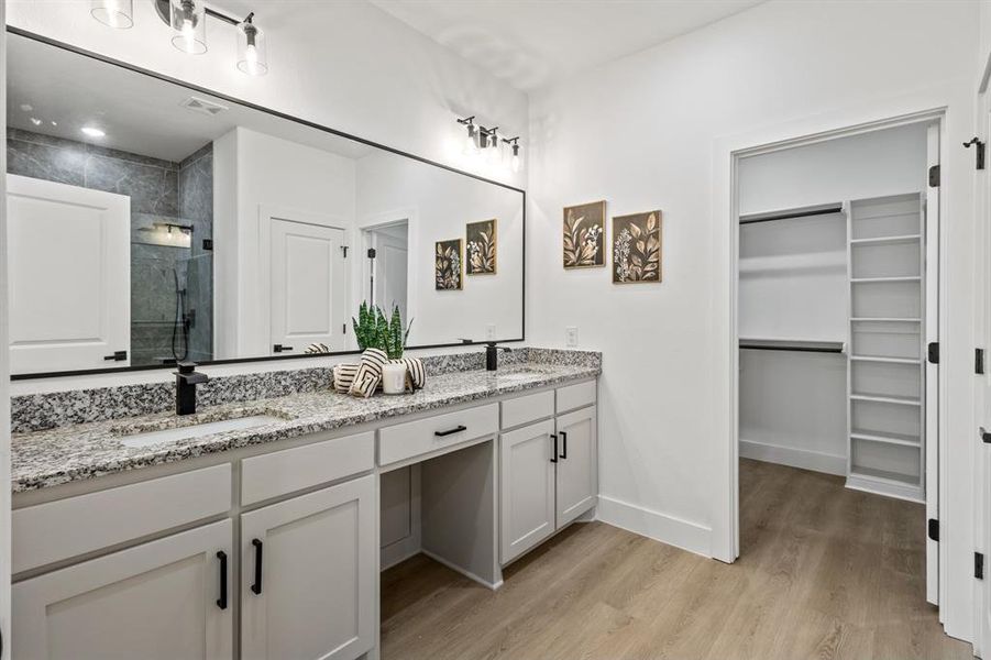 Bathroom with a sink, wood finished floors, a stall shower, and a spacious closet