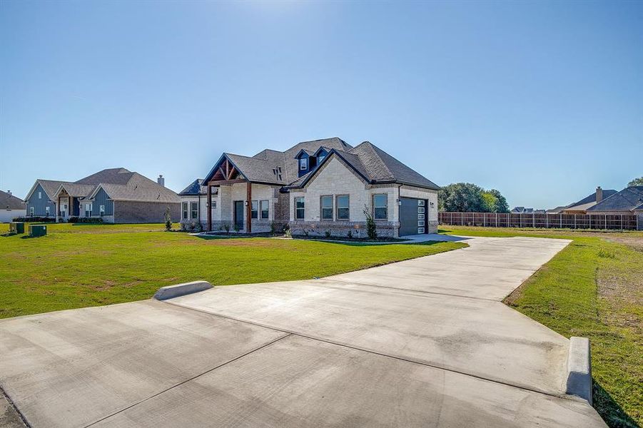 French country style house with stone siding, concrete driveway, and brick siding