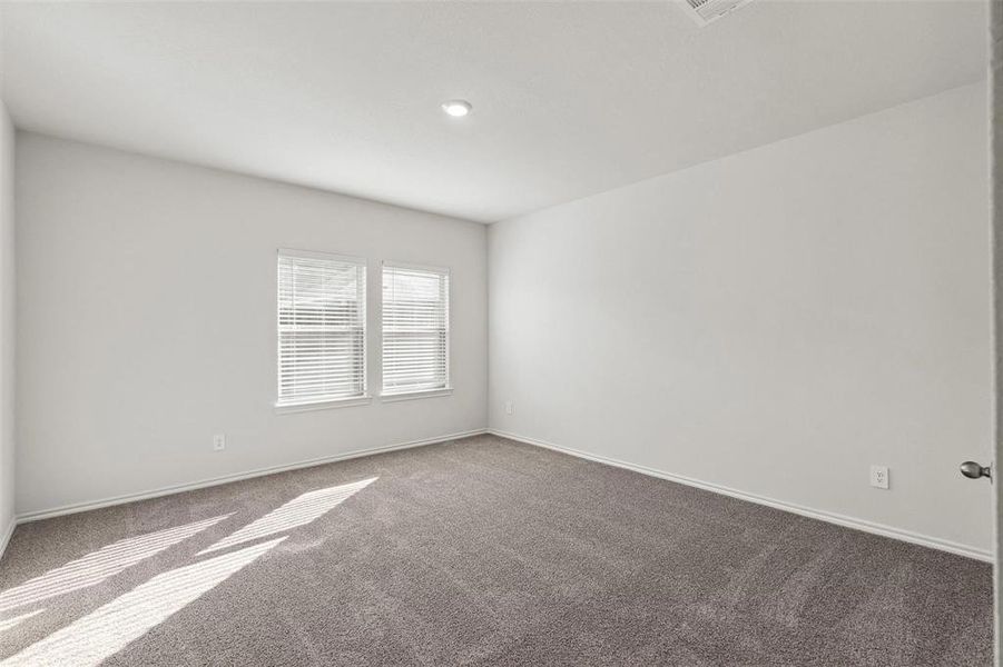 Spacious room featuring neutral carpeting, white walls, and two windows with blinds