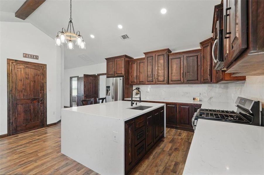 Kitchen with light stone counters, dark brown cabinets, appliances with stainless steel finishes, a center island with sink, and recessed lighting Kitchen with light stone counters, dark brown cabinets, appliances with stainless steel finishes, a center island with sink, and recessed lighting