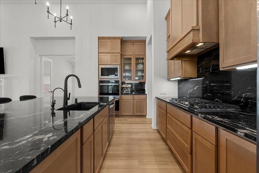 Chef’s kitchen overlooks the spacious living area and boasts double ovens, pot filler, granite countertops, designer backsplash, upgraded cabinetry, stainless steel appliances, stylish finishes, and oversized island seating.