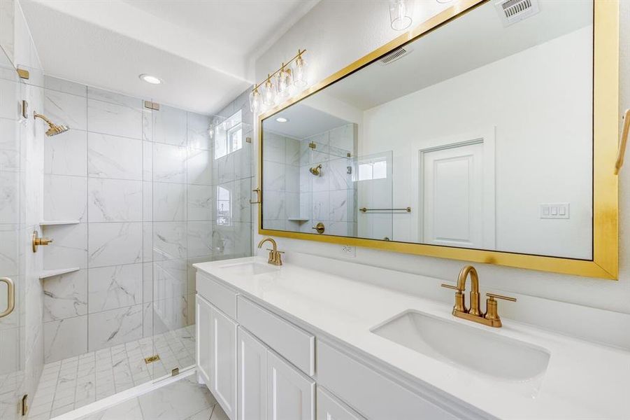 Full bath with double vanity, a marble finish shower, and recessed lighting
