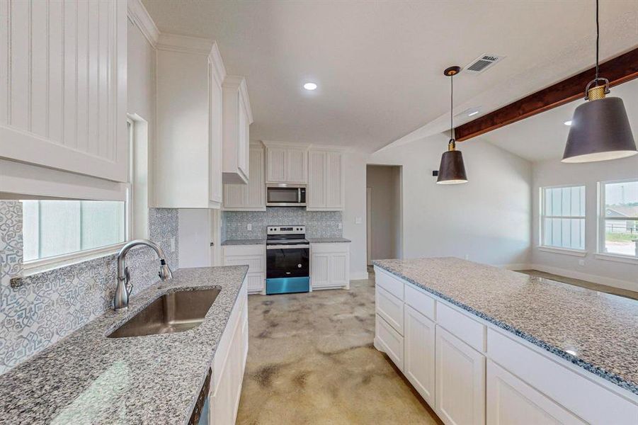 Kitchen with beam ceiling, a wealth of natural light, sink, and stainless steel appliances