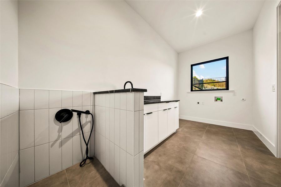Laundry room featuring electric dryer hookup, cabinet space, hookup for a washing machine, and tile walls Laundry room featuring electric dryer hookup, cabinet space, hookup for a washing machine, and tile walls