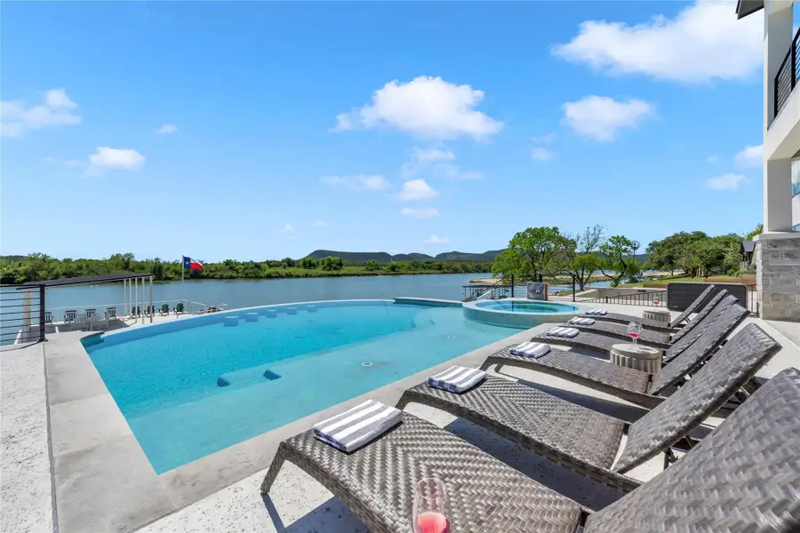 An infinity pool and spa overlook expansive river views from the spacious stone patio.
