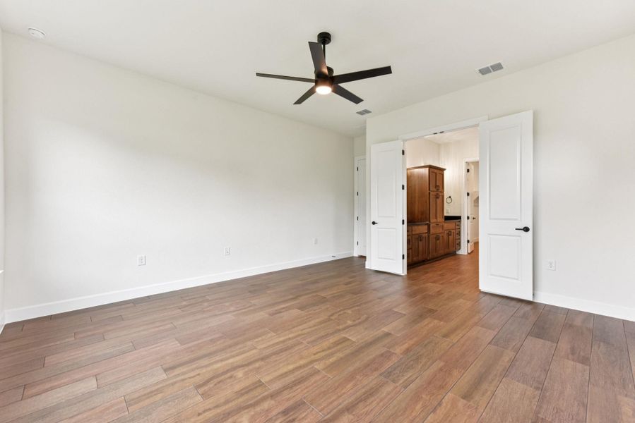 Unfurnished bedroom with a ceiling fan, wood finished floors, and ensuite bathroom