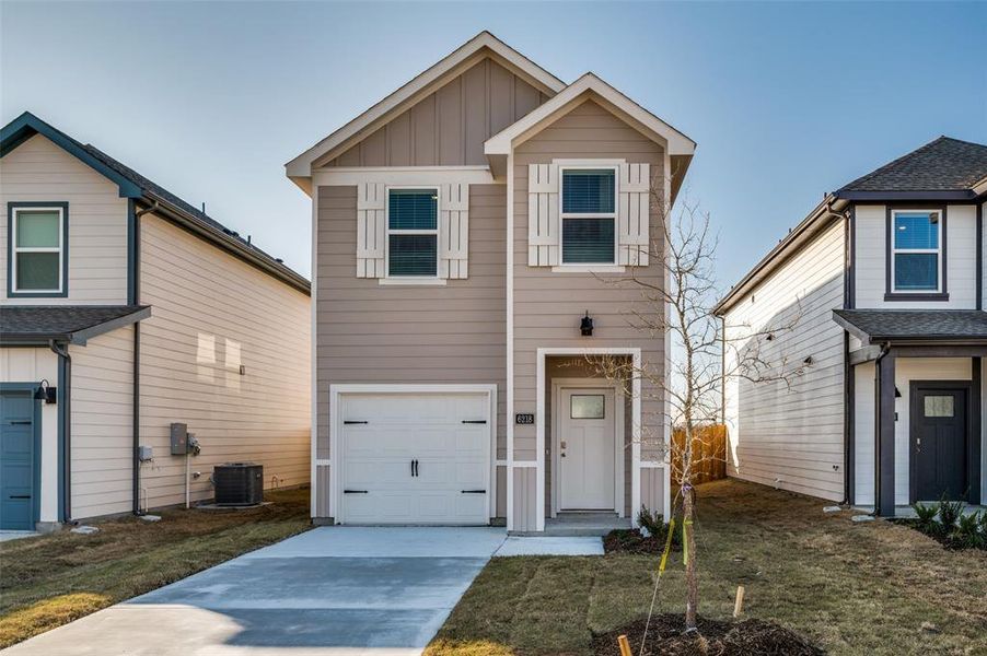 Front facade featuring cooling unit, a garage, and a front lawn