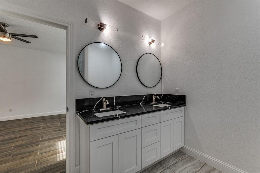 Bathroom with a textured wall, double vanity, wood tiled floors, and a ceiling fan Bathroom with a textured wall, double vanity, wood tiled floors, and a ceiling fan
